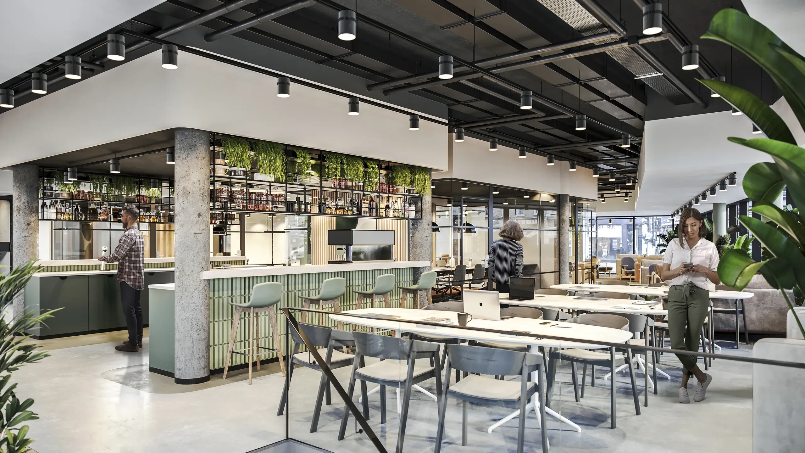 Modern office break room with bar seating, dining tables, concrete columns, green accent walls, plants, and pendant lighting under exposed black ceiling grid.
