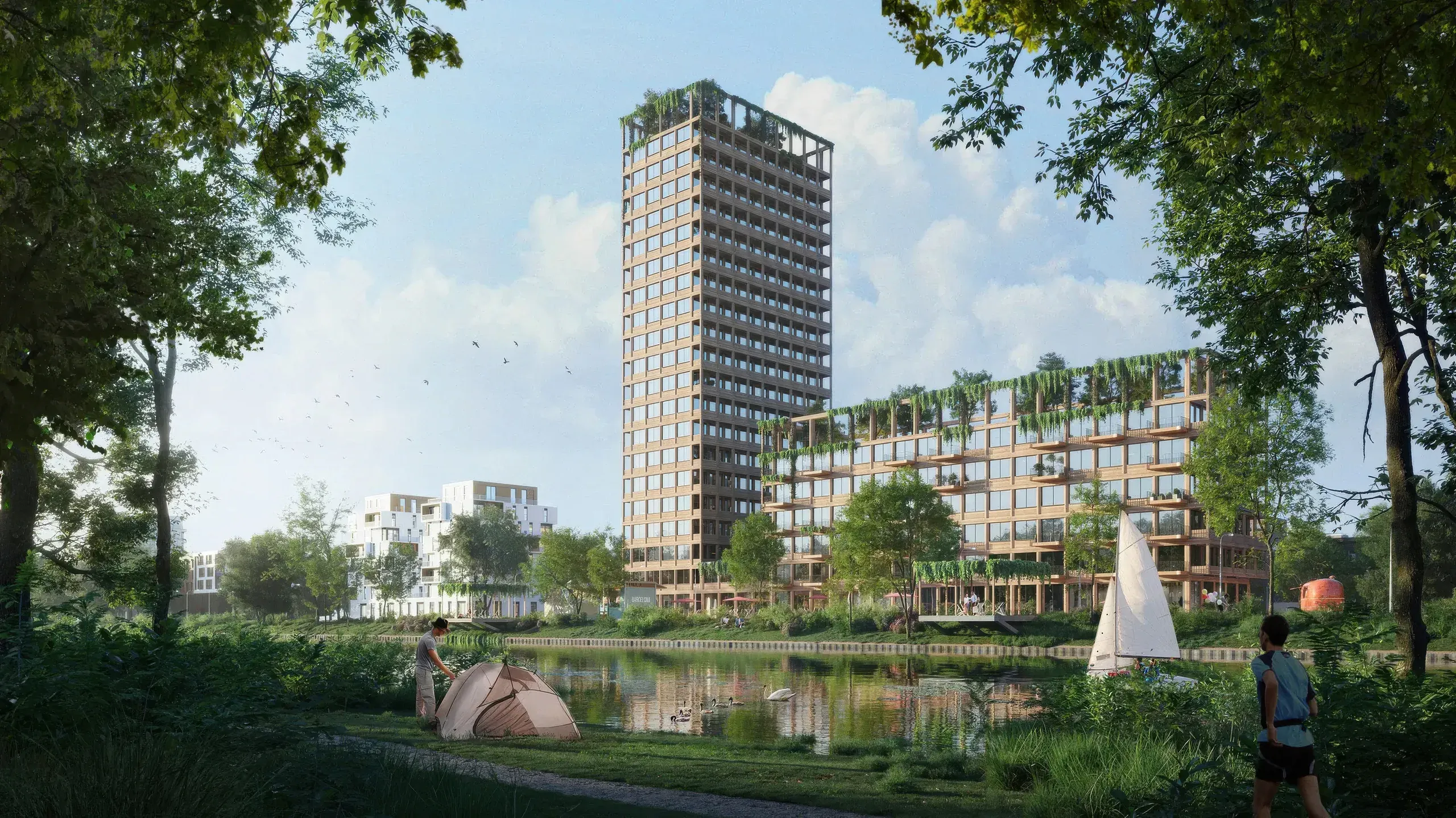 Modern waterfront residential development with tall tower, green terraces, and surrounding buildings overlooking a canal with boats and trees.