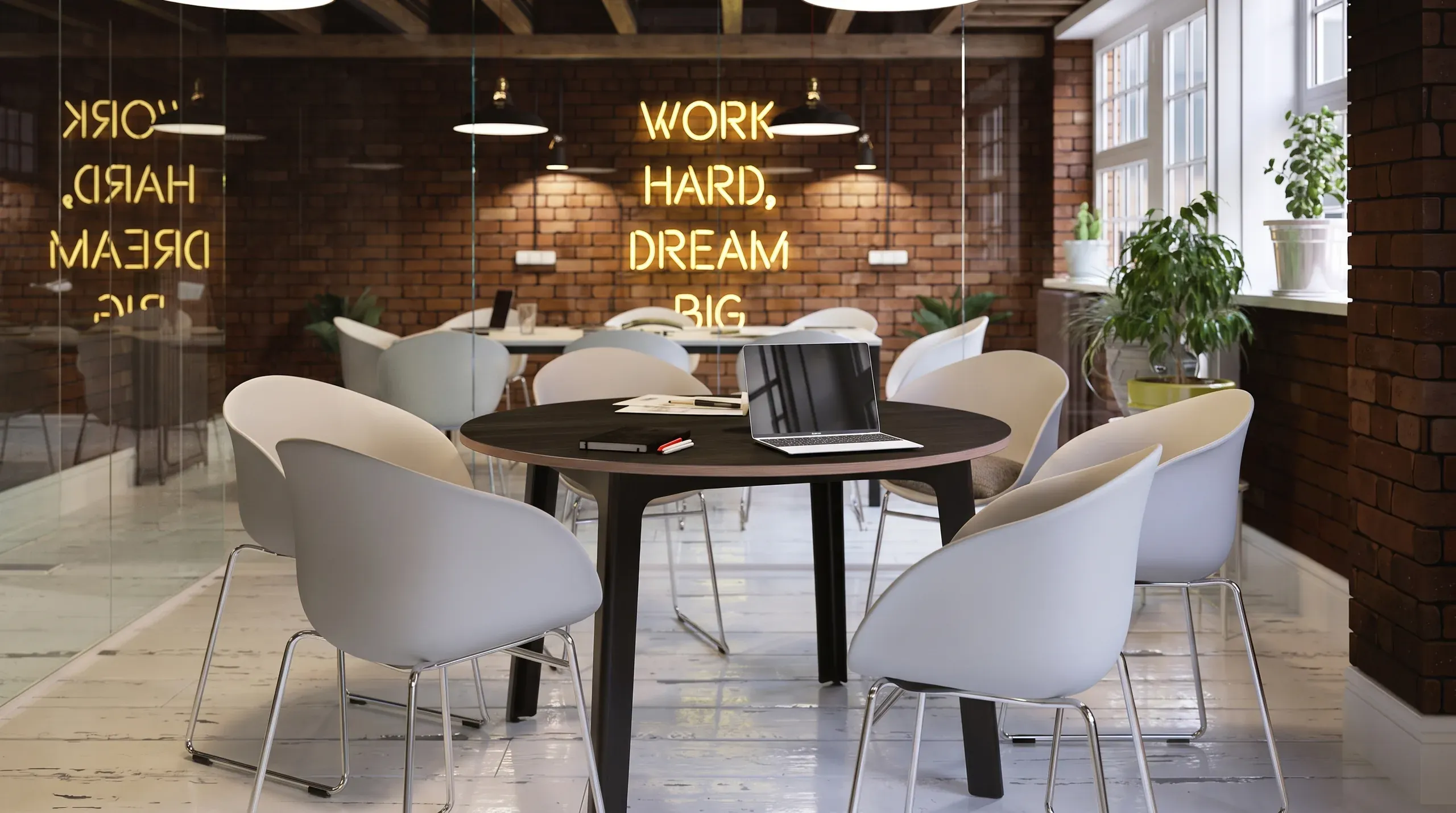Modern office break room with round black table, white chairs, brick walls, and neon yellow "WORK HARD, DREAM BIG" sign above.