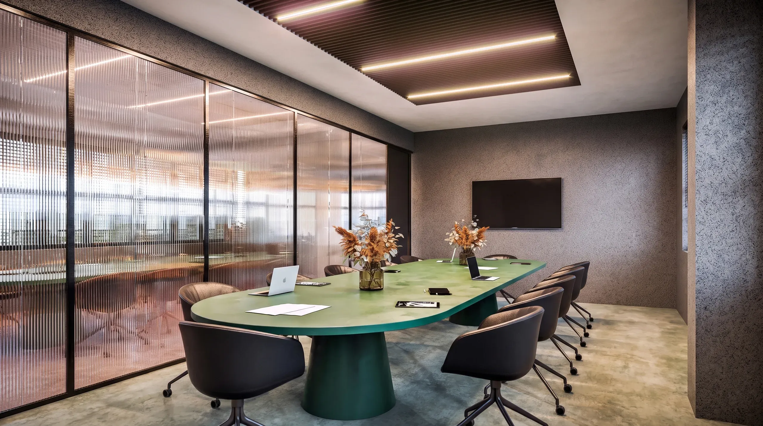 Modern conference room with green oval table, black chairs, floor-to-ceiling windows with textured glass, and linear ceiling lights.