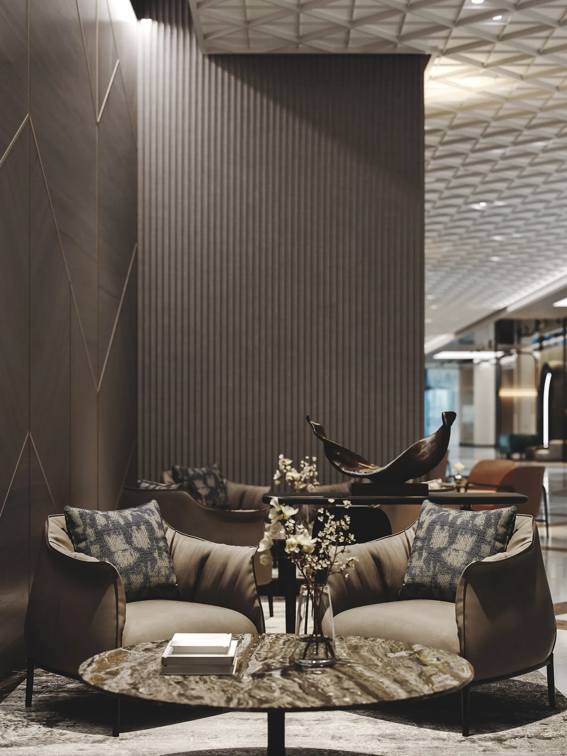 Modern lounge area with two beige curved armchairs, round marble table, decorative sculpture, and vertical ribbed wall panels under geometric ceiling.