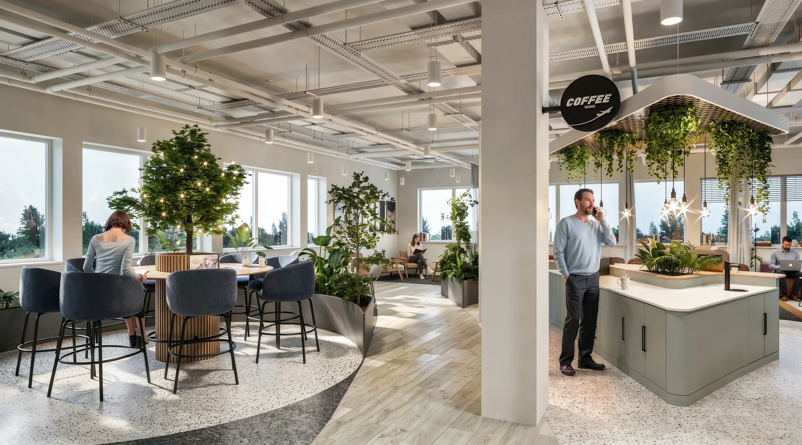 Modern office break room with coffee station, high ceilings, hanging plants, natural light, and lounge seating areas with employees.