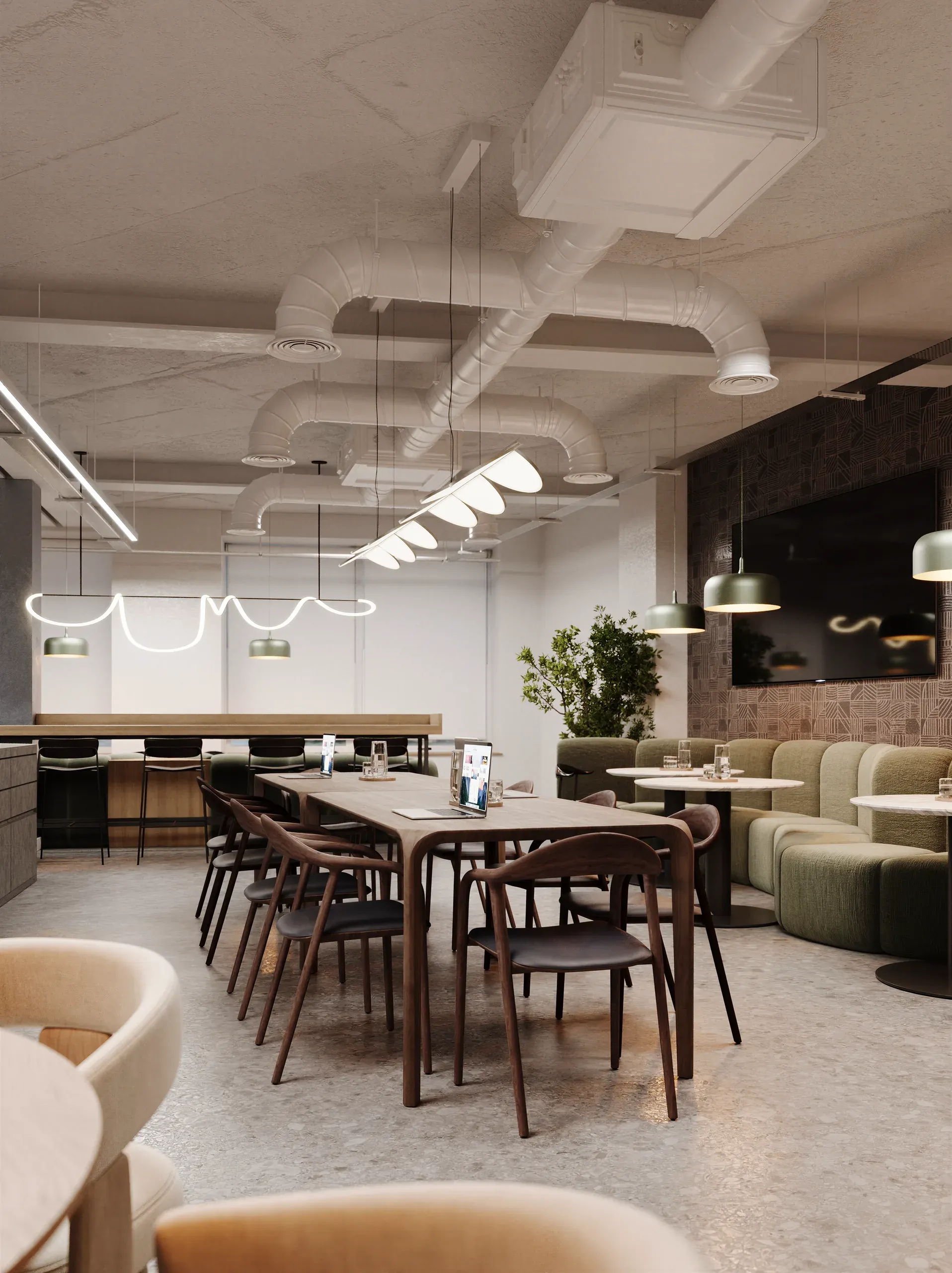 Modern office lounge with wooden dining table, mid-century chairs, green sofas, neon pendant lights, and exposed ceiling ductwork in neutral tones.