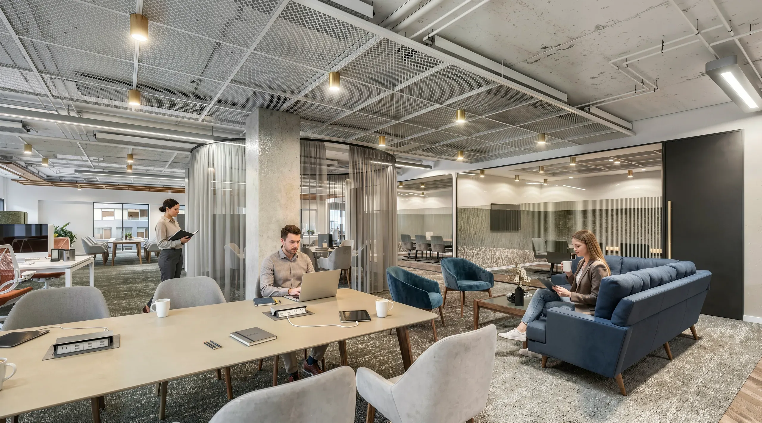 Modern office space with open-plan layout, collaborative seating areas with blue chairs, wooden tables, glass partitions, and professionals working on laptops.