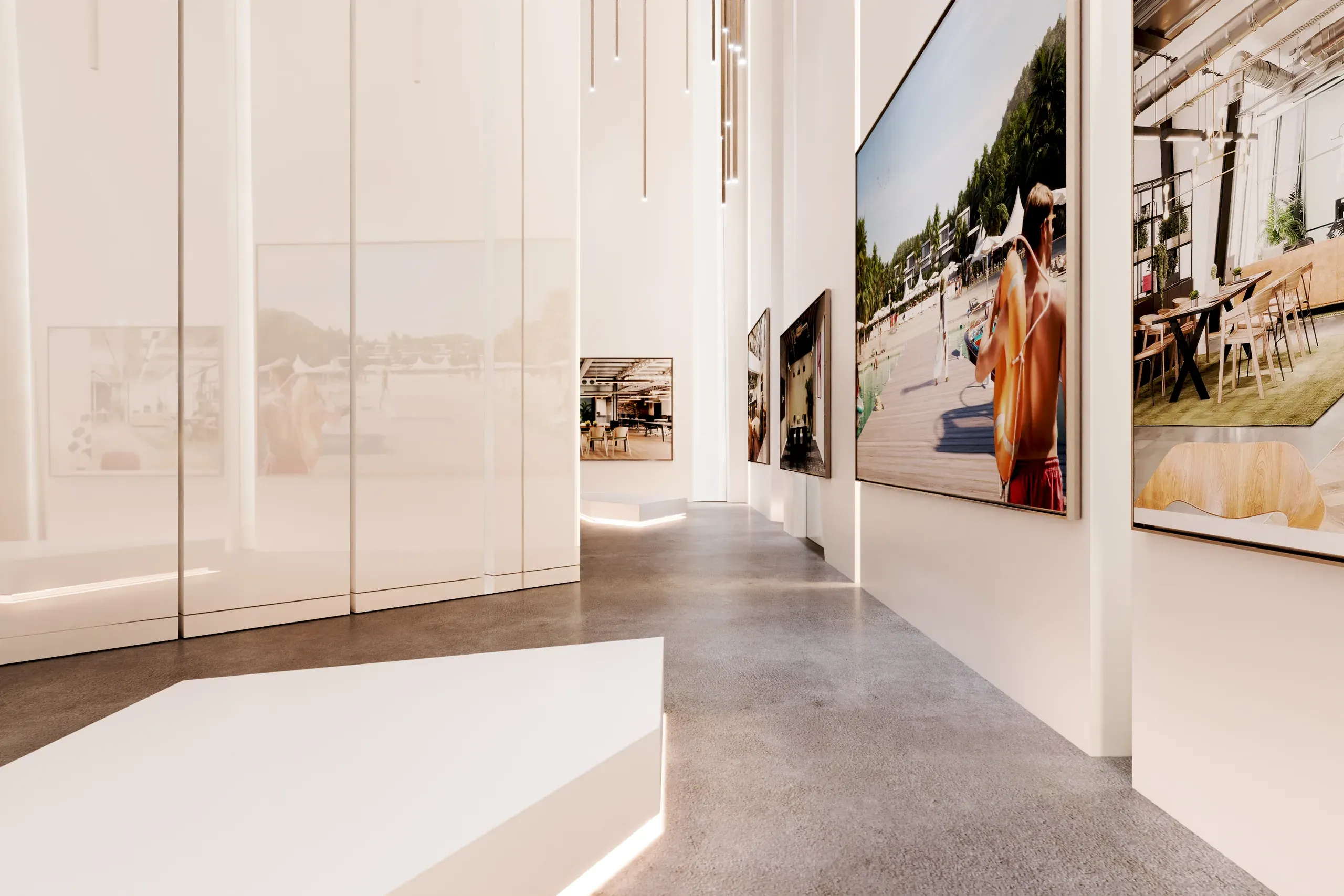 Modern gallery interior with white walls, gray flooring, framed photographs of outdoor spaces, and minimalist architectural design elements.