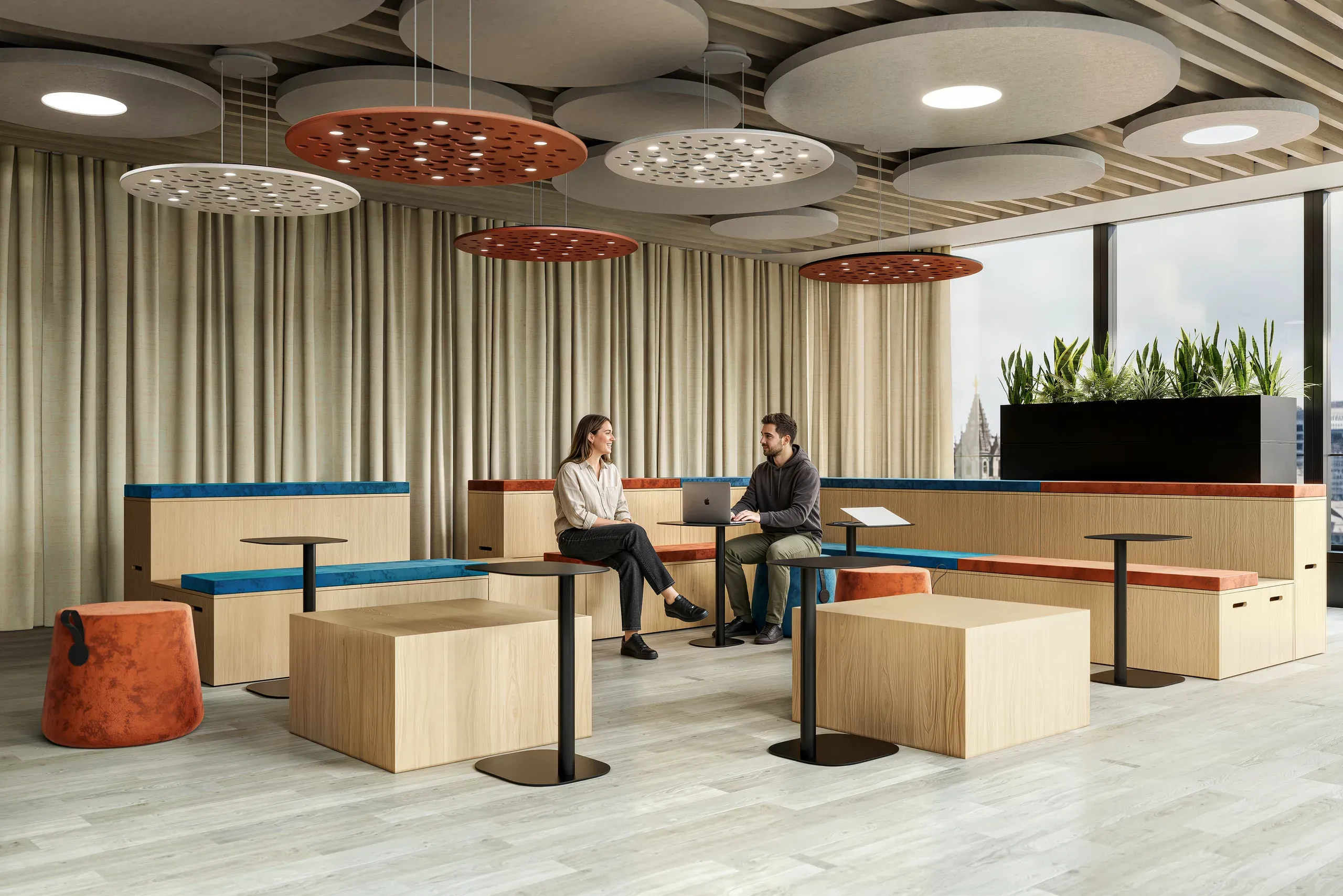 Modern office breakroom with wooden built-in seating, blue and rust-colored accents, pendant lighting, and two people collaborating at a table.