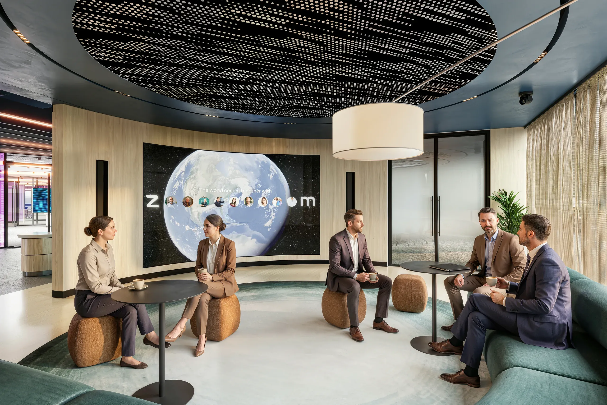 Modern office lounge with six professionals having a meeting around tables and seating, with a large illuminated globe display on the curved wall behind them.
